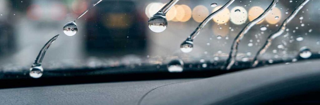Wasser perlt von einer professionell versiegelten Autoscheibe ab und sorgt für bessere Sicht bei Regen in Braunschweig.