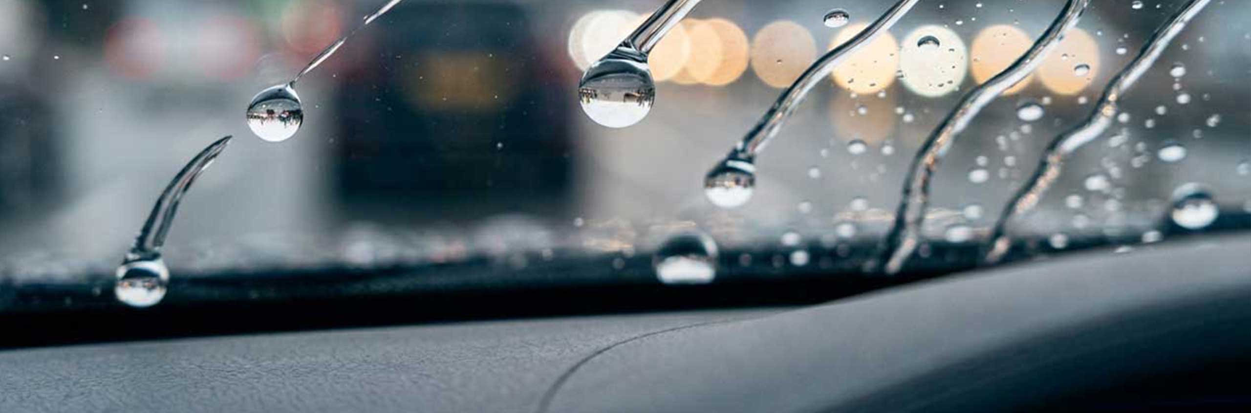 Wasser perlt von einer professionell versiegelten Autoscheibe ab und sorgt für bessere Sicht bei Regen in Braunschweig.